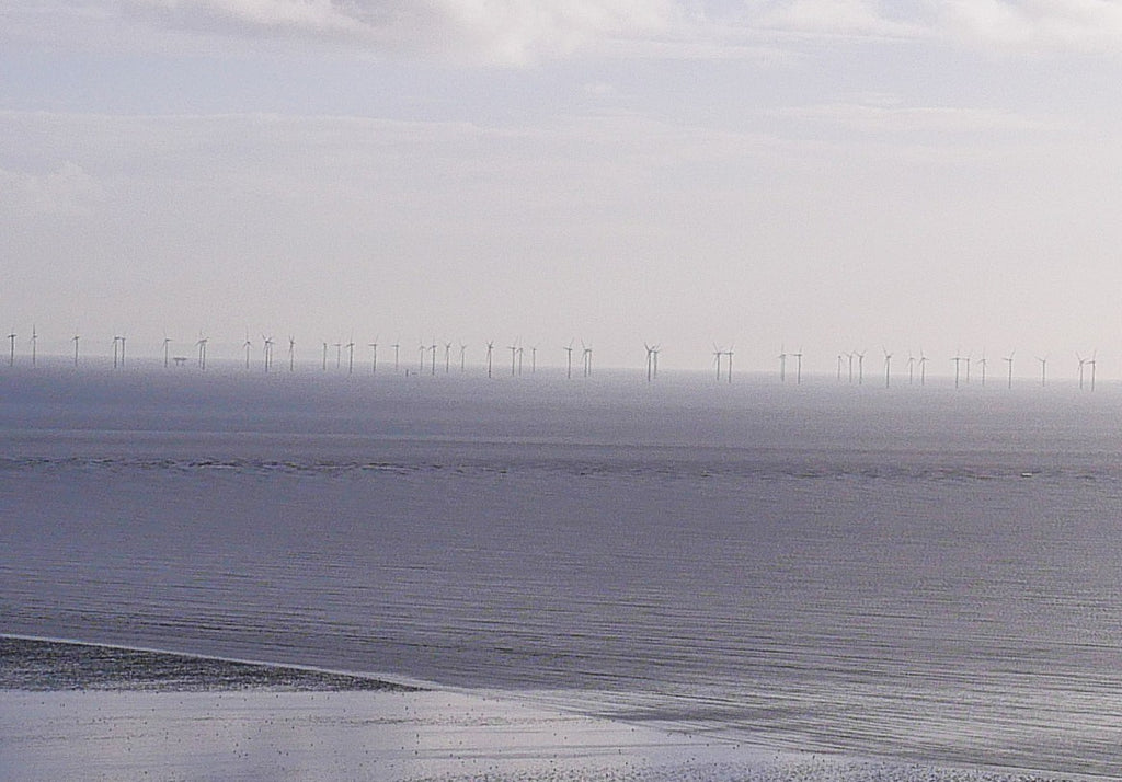 Wind turbines along a coastline with a cloudy sky