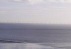 Wind turbines along a coastline with a cloudy sky